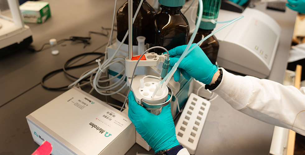 Photo of two hands wearing teal colored latex gloves holding experiment in lab.